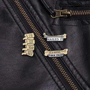 Detailed close-up of funny skeletal enamel pins on a leather jacket showing bone designs