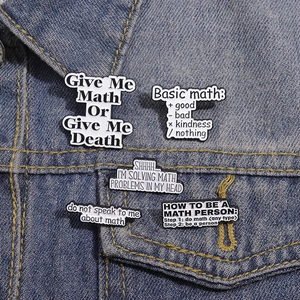 Set of five black and white math-themed enamel pins displayed on a blue denim jacket