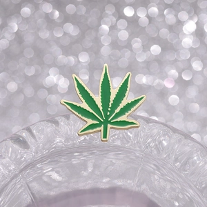 Broche créative en émail feuille verte avec bord doré sur fond de cristal décoratif