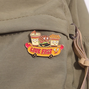 Macro detail of cartoon fast food skateboard enamel pin featuring Live Fast text on canvas