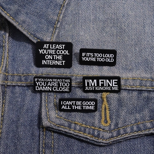 Set of 5 black enamel pins with funny phrases pinned on blue denim jacket