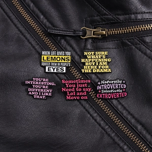 Macro detail of five colorful enamel quote brooches pinned on a black leather jacket