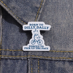 Detail of cute bear riding bike enamel pin on dark blue denim fabric texture