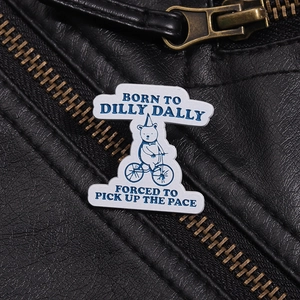 Detail of cartoon bear bicycle enamel pin on black leather jacket with slogan text