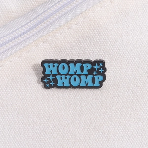 Dettaglio della spilla smaltata blu WOMP WOMP su borsa in tela color bianco crema