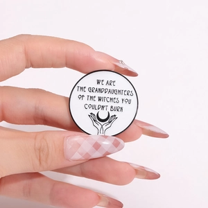 Round minimalist moon and hands enamel brooch with feminist typography on pink background