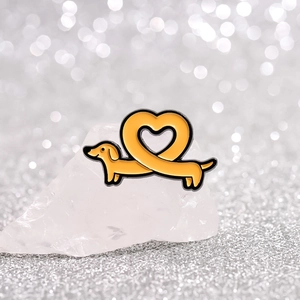 Broche teckel en émail jaune avec corps en forme de cœur sur fond bokeh argenté