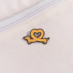 Détail macro d'un pin's en émail teckel jaune en forme de cœur sur tissu en toile