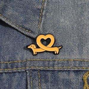 Broche créative en émail en forme de teckel cœur sur le col d'une veste en jean