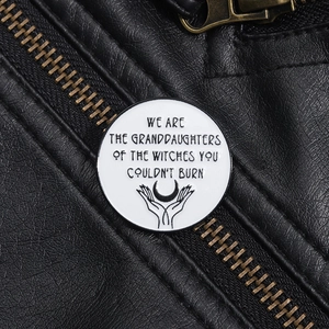 Detail of round enamel brooch with feminist quote on black leather jacket background