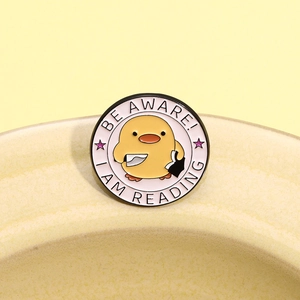 Cartoon Enamel Pin mit kleiner gelber Ente und 'Be Aware I Am Reading' Schriftzug