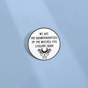 Minimalist enamel pin featuring hands holding moon design and artistic typography on blue