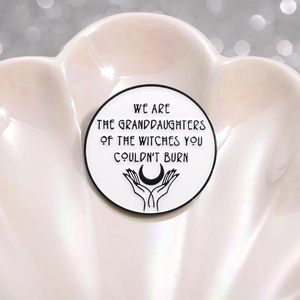 Minimalist white enamel brooch with black text and mystical crescent moon design