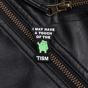 Close-up of green frog enamel pin with funny text on a black leather jacket lapel