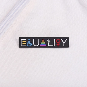 Close-up of Equality enamel pin with rainbow symbols on white canvas background