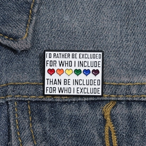 Close-up of a rectangular enamel pin with rainbow hearts on a blue denim jacket