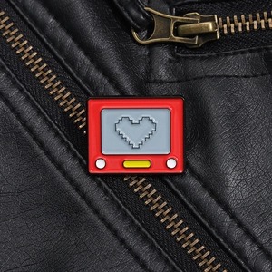 Makroaufnahme einer roten Retro-TV-Emaille-Nadel mit Pixelherz auf einer Lederjacke