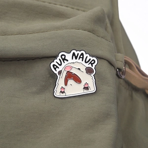 Close-up of screaming cartoon opossum enamel pin with AUR NAUR text on green canvas