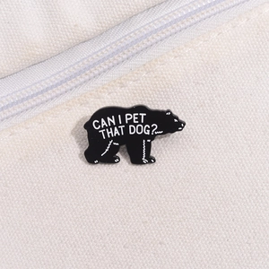 Detail of a black enamel pin with text CAN I PET THAT DOG pinned on a canvas bag