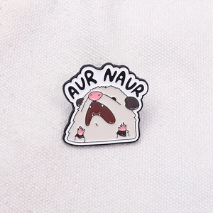 Détail d'un pin's rigolo en émail avec texte AUR NAUR sur fond de toile blanche