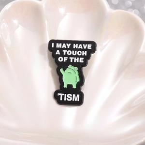 Funny green frog enamel pin with I MAY HAVE A TOUCH OF THE TISM text on shell tray