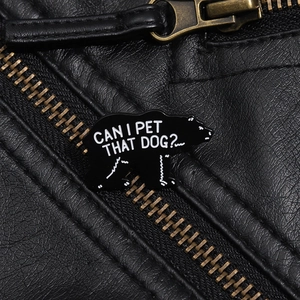 Detail einer schwarzen Bären-Emaille-Anstecknadel mit Text auf einer Lederjacke