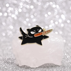 Black cat enamel brooch with knife and crime text on a sparkling silver background