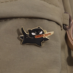 Funny black cat enamel pin holding a crime dagger, quirky cat badge on a canvas bag