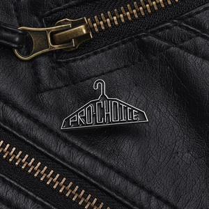 Detail of Pro-Choice black enamel clothes hanger brooch pinned on a black leather jacket