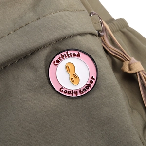 Macro shot of circular enamel pin featuring peanut design and Goofy Goober text on canvas
