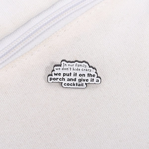Détail d'un pin's en émail en forme de nuage avec une citation familiale humoristique