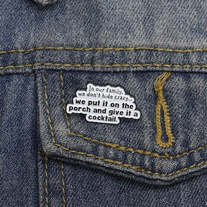 Détail d'un pin's émaillé sur une veste en jean avec un slogan familial drôle
