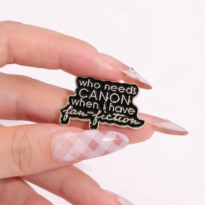Broche en émail noir avec citation fan-fiction dorée et forme métallique unique
