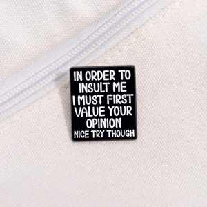 Macro shot of a rectangular enamel pin with a sarcastic quote on white canvas fabric