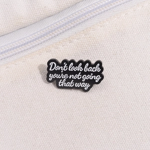 Black enamel brooch with 'Don't look back' inspirational text on white canvas bag