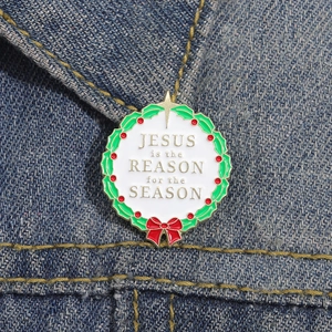 Broche couronne de Noël en émail avec texte Jésus sur une veste en jean bleue