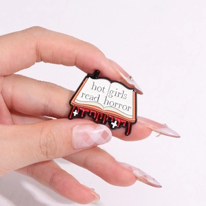 Creative open book metal enamel pin featuring hot girls read horror text and red drip design