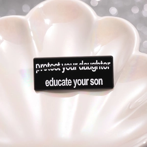 Schwarze Emaille-Brosche mit Aufschrift 'Educate Your Son' auf Perlenschale präsentiert