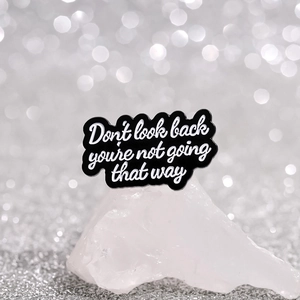 Enamel lapel pin with inspirational text Don't look back displayed on white crystal
