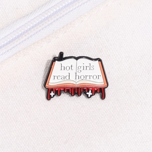 Detail shot of 'hot girls read horror' enamel book pin with red drip effect and crosses