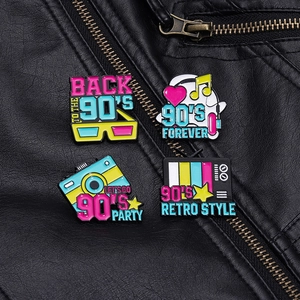 Close-up of retro 90s enamel pins featuring TV and camera on black leather background