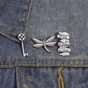 Gros plan de broches vintage en forme de libellé et de clé sur un tissu en denim bleu