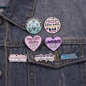 Close-up of pink enamel badges and heart-shaped pins on a blue denim jacket pocket