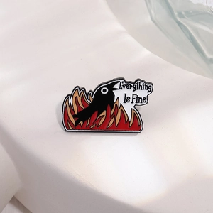 Cartoon raven pin with 'Everything Is Fine' text and red fire base on white stand