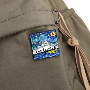 Detail of square Van Gogh style enamel pin showing starry night and snow mountain on fabric