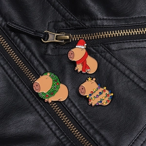 Close-up of three festive Christmas capybara enamel pins on a black leather jacket
