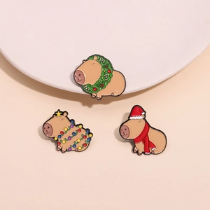 Three cute Christmas capybara enamel pins with festive wreaths and holiday lights decoration
