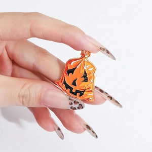 Vista a mano della spilla di zucca smaltata con volto di Halloween e bordi dorati