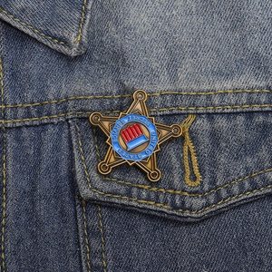 Macro view of vintage bronze pentagram brooch pinned on blue denim jacket pocket