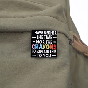 Black enamel pin with humorous text displayed on a khaki canvas bag background